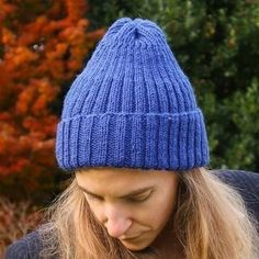 a woman with long hair wearing a blue knitted hat looking down at her cell phone