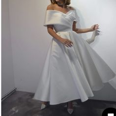 a woman in a white dress posing for the camera with her hands on her hips