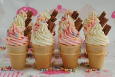 three ice cream cones with sprinkles and chocolate sticks in them on a table