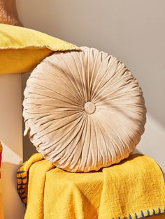 a yellow blanket sitting on top of a bed next to a pillow