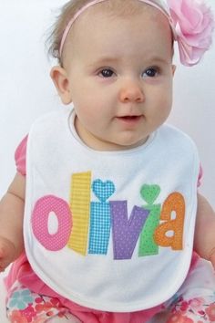 a baby girl wearing a bib with the word olliva on it's chest