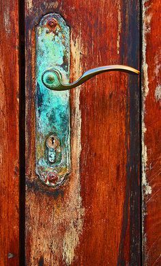 an old door handle with rusted paint on the outside and wood in the inside