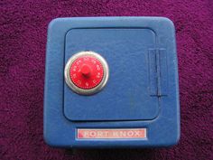 a blue box with a red knob on the side and a purple towel behind it