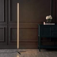 a floor lamp that is on top of a wooden table next to a black cabinet