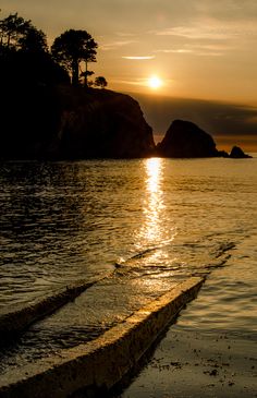 the sun is setting over an island in the middle of the ocean with small rocks