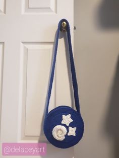 a blue purse hanging from the side of a door with white stars on it and a button at the bottom