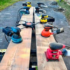 several power tools are lined up on top of wooden planks in a driveway area