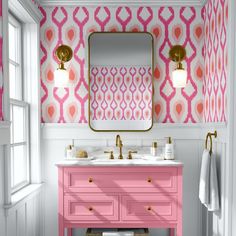 a bathroom with pink vanity, mirror and wallpaper in the background that has gold accents