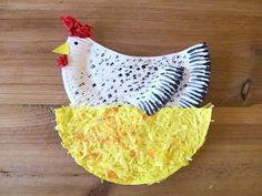 a paper mache chicken sitting on top of a wooden table