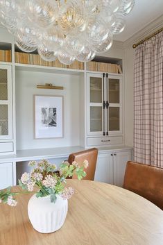 a vase with flowers sitting on top of a wooden table in front of a bookcase