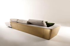 a gold couch with pillows on it in a white room