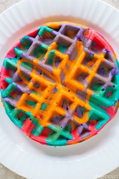 a waffle cake with colorful icing on a white plate