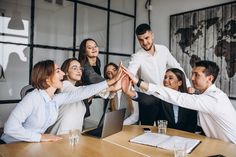 a group of business people giving high fives to each other at a meeting table