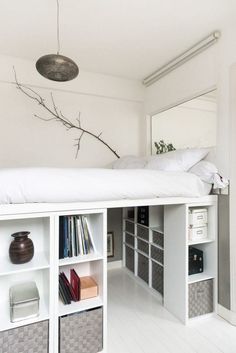 there is a white bed with bookshelves in the corner and a tree branch hanging over it