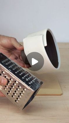 a person holding a grater over a wooden cutting board with a metal grater on it