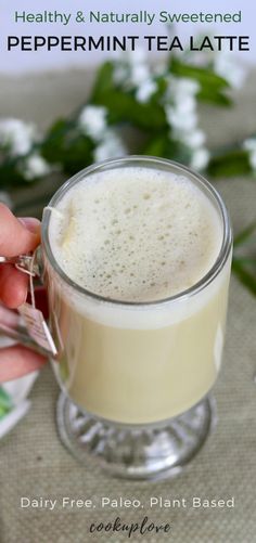 a person is holding a glass mug filled with tea