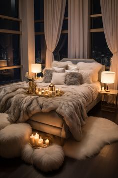 a large bed with candles on it in a bedroom next to two lamps and windows