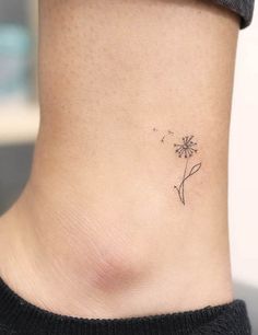 a small tattoo on the ankle of a woman with a dandelion in it