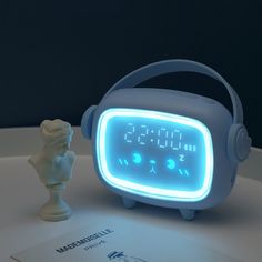 a blue alarm clock sitting on top of a table next to a white busturine