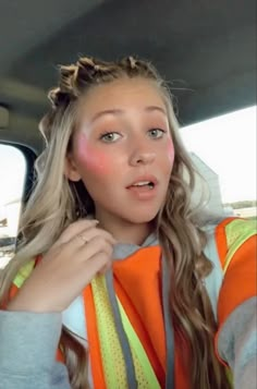 a woman in an orange safety vest is looking at the camera and has her hand on her shoulder