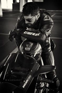 black and white photograph of a man leaning on a motorcycle