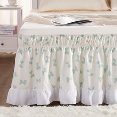 a bed with a white bedspread and blue butterflies on the ruffles