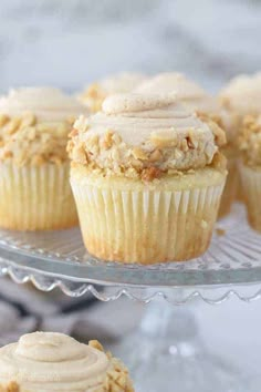 cupcakes with frosting on a glass cake plate