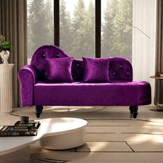 a purple couch sitting in front of a window next to a white table and chair