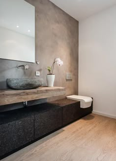 a bathroom with a sink, toilet and mirror on the wall next to wooden flooring