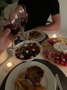 a man sitting at a table with plates of food and wine in front of him