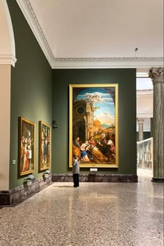 a person standing in front of paintings on the wall at an art gallery with marble flooring