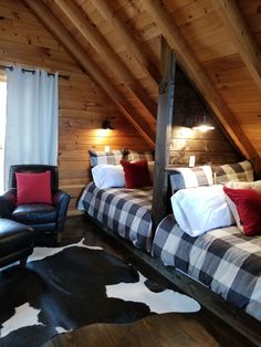 a bed room with two beds covered in blankets and pillows on top of it next to a chair