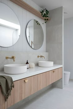 a bathroom with two sinks and a round mirror