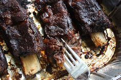 the ribs are being cooked on the grill with a fork