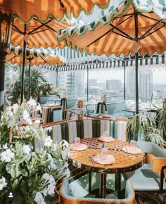 an outdoor dining area with tables, chairs and umbrellas over looking the cityscape