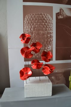 red flowers are placed on top of a white stand