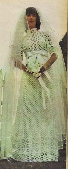 an old photo of a woman wearing a wedding dress and holding a bouquet in her hand