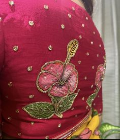 the back of a woman's red blouse with gold and pink flowers on it