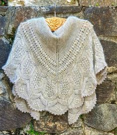 a crocheted shawl hanging on a stone wall