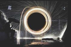 a person holding an umbrella standing in front of a firework circle with long exposure