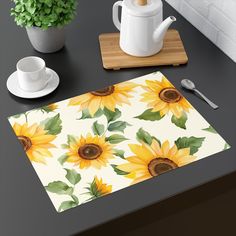 a place mat with sunflowers on it next to a cup and saucer