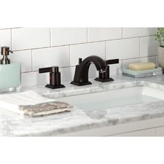 a bathroom sink with two faucets and soap dispenser