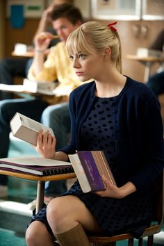 a woman sitting at a desk with books in her hands