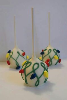 four cake pops decorated with christmas lights and icing are on a white table top