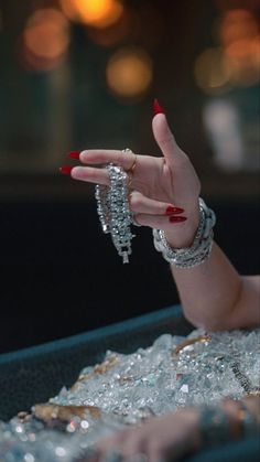 a woman's hand with red nail polish and bracelets