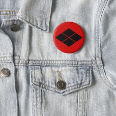 a red button with an image of a black diamond on it in the pocket of a jean jacket