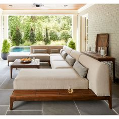 a living room filled with furniture next to a swimming pool on top of a stone floor