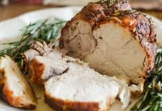 a white plate topped with meat covered in gravy and garnished with herbs