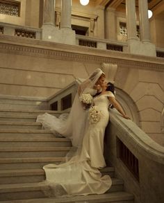 two brides posing on the stairs in front of an ornate building with columns and pillars