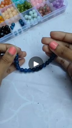 two hands are holding beads and making a beaded bracelet